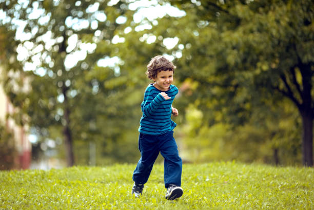 istock Cute boy running across grass und smiling. 1321109407