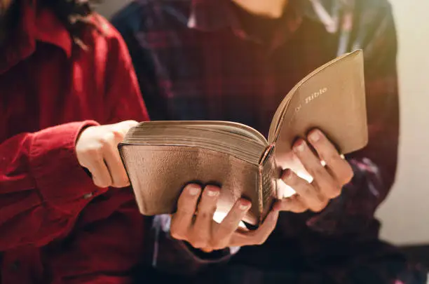 Photo of A woman and two men were studying and reading the Bible. That is Christian love