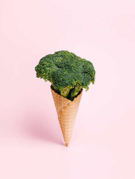 istock Fresh broccoli in an ice cream cone on pastel pink background. Waffle cone with a vegetable as a vegetarian dessert. Creative healthy food concept. 1321110300