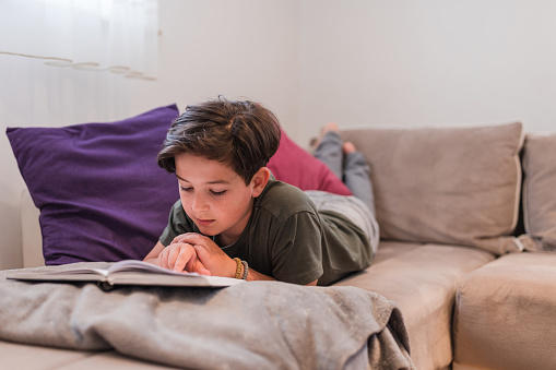 Kid resting at home and reading a book