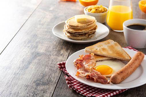 Grand Slam Breakfast with Pancakes, Bacon, Sausages Sunny Side up Eggs and Toast