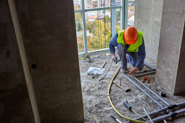 istock Worker or builder in workwear and safety helmet is installing plastic pipes using modern tools in a flat of building under construction 1321114513