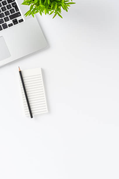 istock Laptop, notebook, pen and flower on white background with copyspace. Office desktop concept. Top view 1321116413