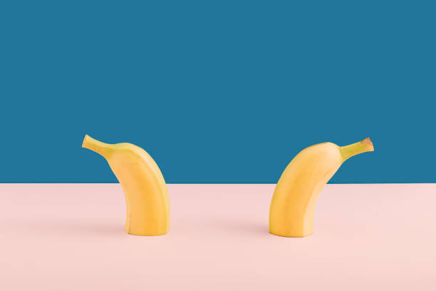 istock Minimalistic modern food idea with halved fresh bananas on pink and blue background. Creative colorful summer concept, geometric arrangement. 1321119992