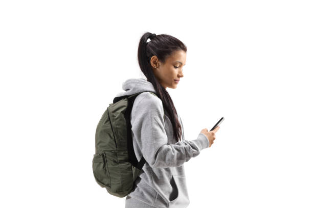 istock Student with a backpack walking and looking into a mobile phone 1321120161