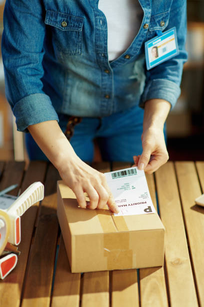 istock Modern female in office applying shipping label to parcel 1321120213