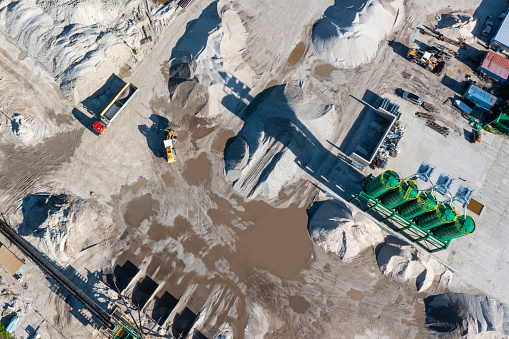 Aerial view of excavator moving sand in an open gravel pit.