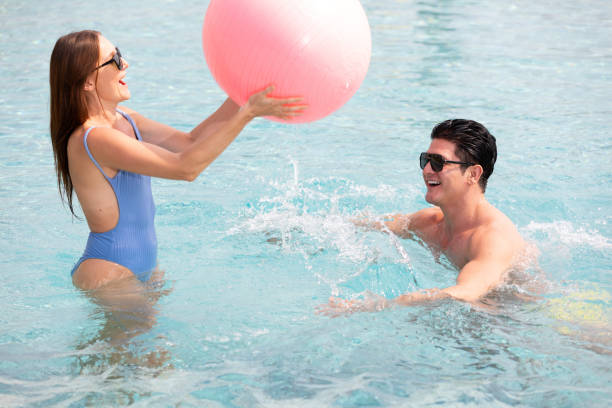 istock couple having fun in pool and playing with a ball 1321123413