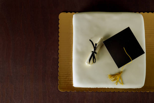 istock Graduation white cake with cap on the top and diploma decor. 1321123537