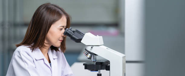istock A young scientist woman in a laboratory coat looking through a microscope in a laboratory to do research and experiment. Scientist working in a laboratory 1321123895
