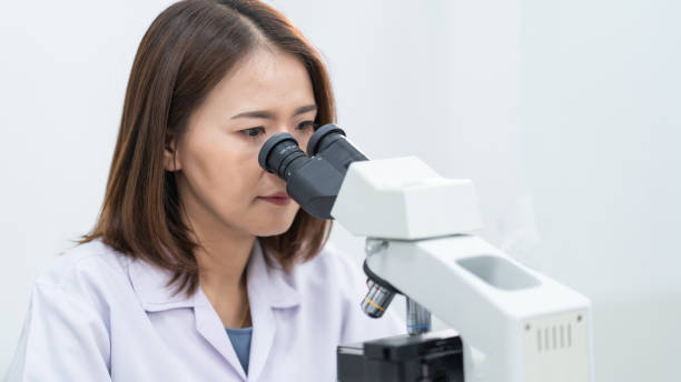 istock A young scientist woman in a laboratory coat looking through a microscope in a laboratory to do research and experiment. Scientist working in a laboratory 1321123921