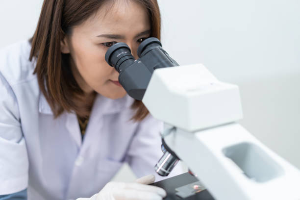 istock A young scientist woman in a laboratory coat looking through a microscope in a laboratory to do research and experiment. Scientist working in a laboratory 1321125076