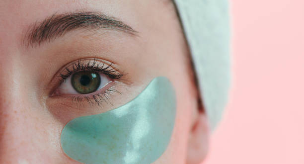 Cropped studio portrait of a young woman with an eye treatment on her face against a pink background Puffy eyes are a thing of the past one eyed stock pictures, royalty-free photos & images