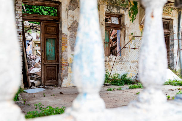 Broken door and  windows on old abandoned house with plants growing inside. The ruins of a Mediterranean house