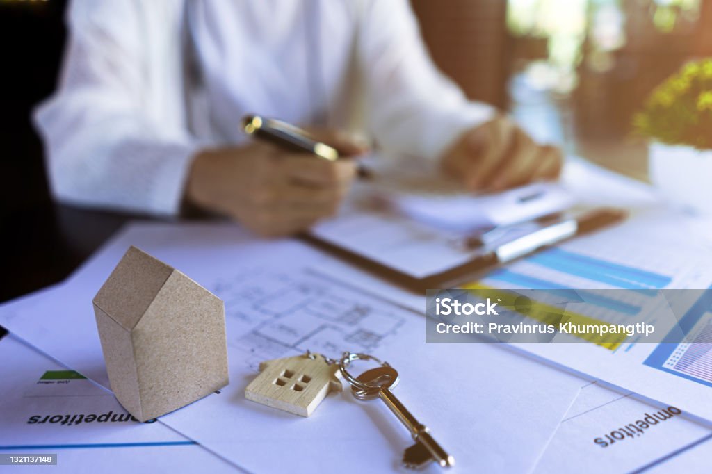 Professional Real estate agents calculate the price of housing with a house keys, miniature model houses,  house design documents. Mortgage Broker Stock Photo