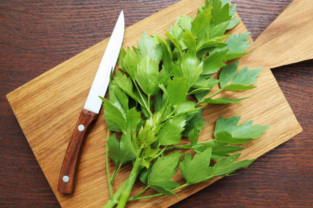 foglie verdi fresche di lovage o levisticum officinale su un tagliere in legno - levisticum officinale foto e immagini stock