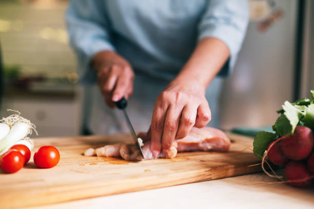 istock Female hands cutting white meat in the kitchen 1321143256