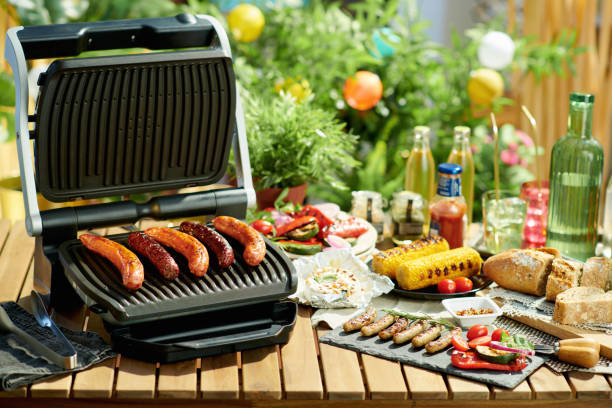 istock desk with electric grill, grilled sausages and corn 1321143375