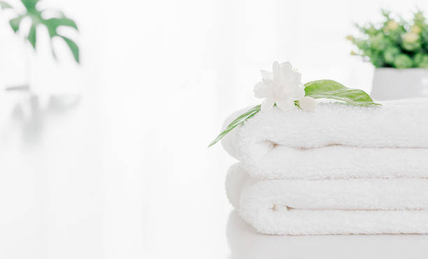 istock Folded soft terry towel and flower on white table with copy space. 1321144525