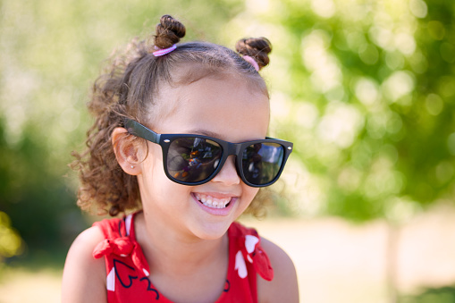 funny portrait of little baby girl wearing vintage colored glasses outdoors in a park