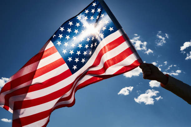 istock Waving usa flag in hand against blue sky 1321146718