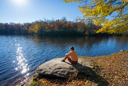Man relaxing by the beautiful lake. Hiker sitting by the lake in the autumn forest. Price Lake by Blue Ridge Parkway, near Blowing Rock, North Carolina, USA