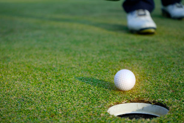 istock White golf ball near hole on green grass. 1321151573