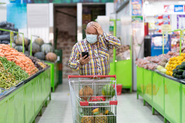 istock elderly man with mask conducts market inside a grocery store checking his cell phone while doing market 1321153497