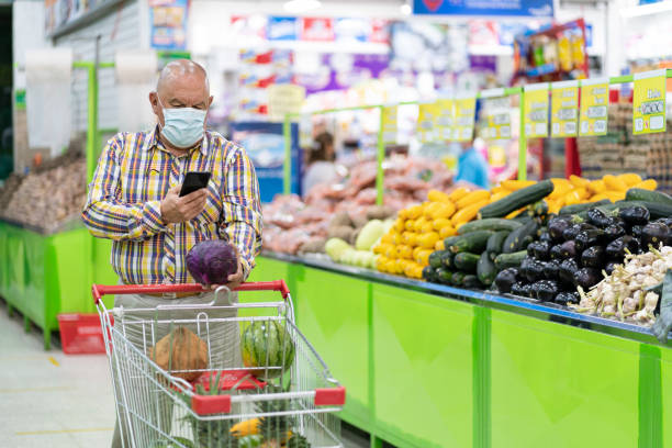 istock elderly man with mask conducts market inside a grocery store checking his cell phone while doing market 1321153621