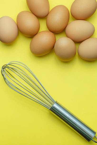 istock egg and egg beater on yellow background,Chicken eggs, brown eggs, broken egg in carton box on yellow background. Top view natural eggs in carton box product concept 1321155412