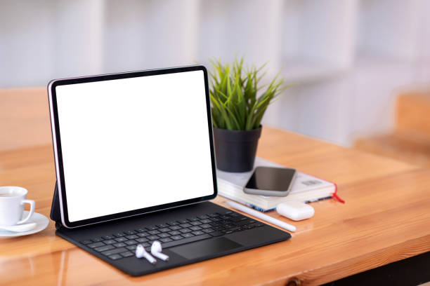 istock Tablet computer white screen with a set of headphones placed on a wooden table. 1321157524