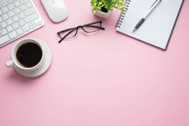 istock Desk with coffee keyboard notebook glasses on pink background. Copy space. 1321158075