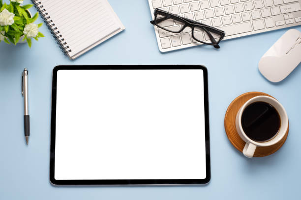 istock Workspace desk with coffee mug keyboard glasses mouse on a blue background. Copy space. 1321158107