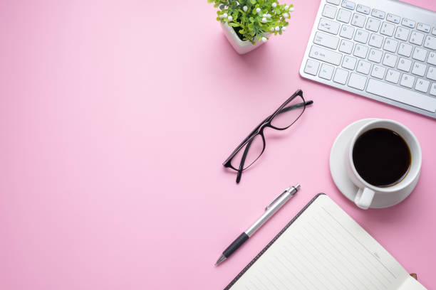 istock Pink office desk with keyboard, glasses, coffee mug are placed at office. Copy space. 1321158118