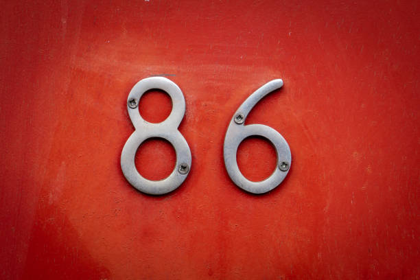 Silver chrome door number 86 eighty sic screwed onto wood painted bright red.