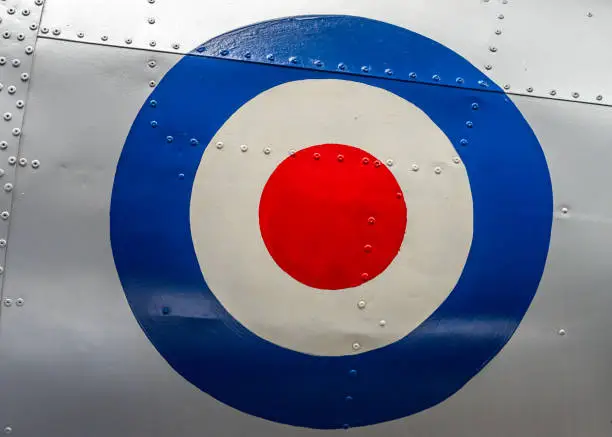 Large retro RAF target symbol on abandoned old aeroplane. Silver metal fuselage with rivets on historic decommissioned fighter plane from WW2 shiny and clean.
