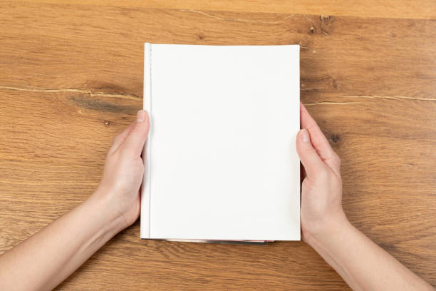 istock Woman's hands open empty catalog, magazines, book mockup on wooden table 1321166009