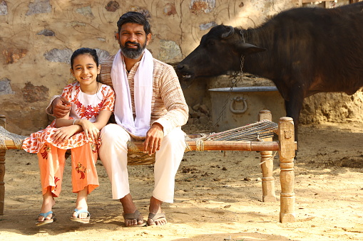A rural Indian family of a Father and a Daughter Sitting outdoor in  summer noon.