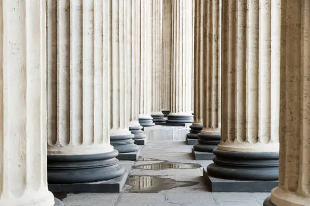 High marble columns as background, architectural design in style of classicism. Architectural pattern of pillars in space. Monochrome ivory white color. Horizontal image.