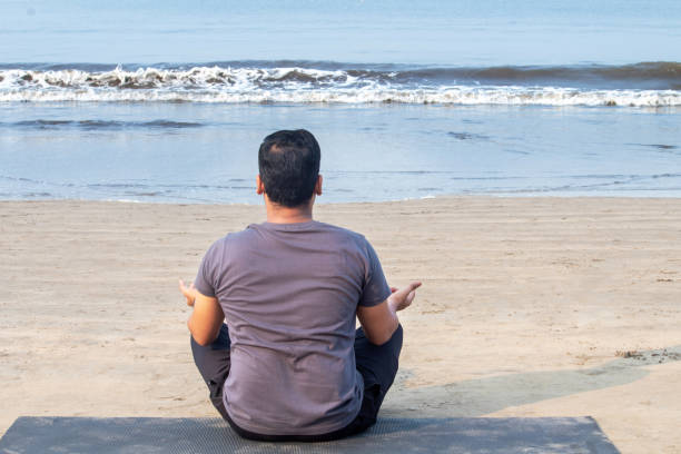 istock Man practicing yoga in lotus position at seafront 1321169021
