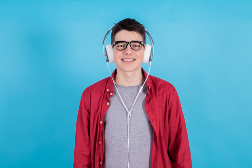 young teenage man with headphones isolated on blue background