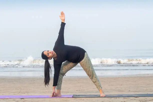 Woman practicing yoga pose early morning at beach