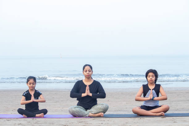 istock Mother with son and little daughter meditating at beach 1321171397