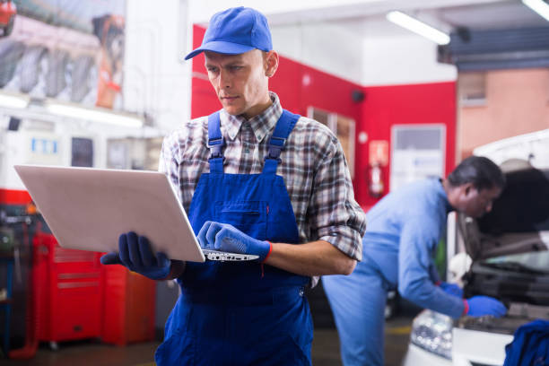 istock Male mechanic using laptop while repairing car in service 1321171414