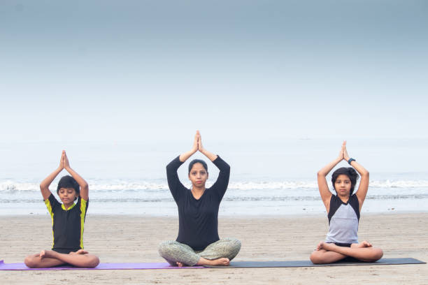 istock Woman with children practicing yoga exercises on beach 1321171685