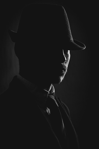 Retro man in hat wears suit and tie, black and white. Noir style.