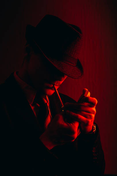 istock Retro man in suit and hat lighting a cigarette 1321172521