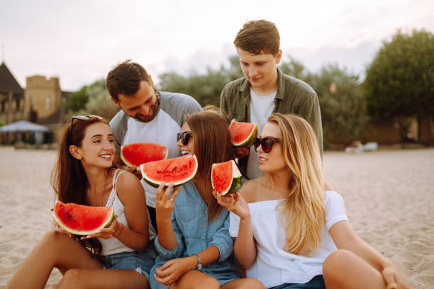 istock Young friends relaxing on the beach and eating watermelon. 1321174029