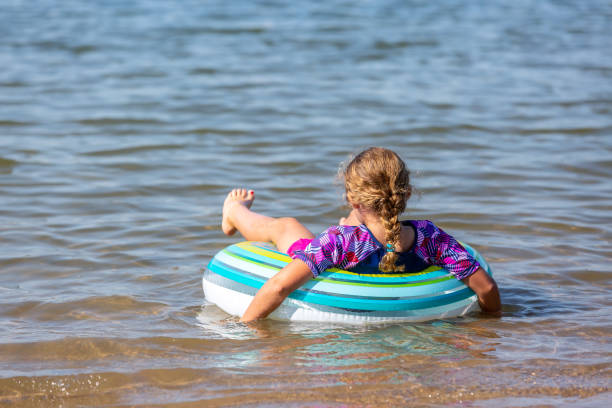 девушка, плавающая на внутренней трубе float игрушка в воде - inner tube swimming lake water стоковые фото и изображения