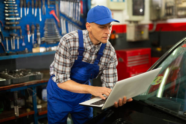 istock Male mechanic using laptop while repairing car in service 1321175188